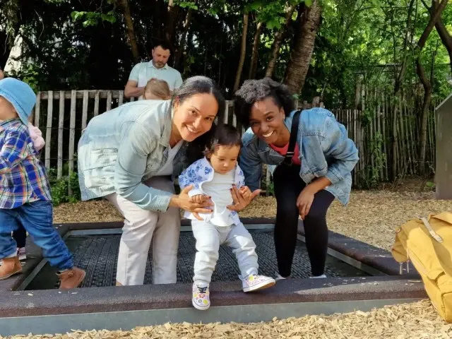 Two women in their early 30s having fun together and playing with a small cChild. Showing friendship and support.
