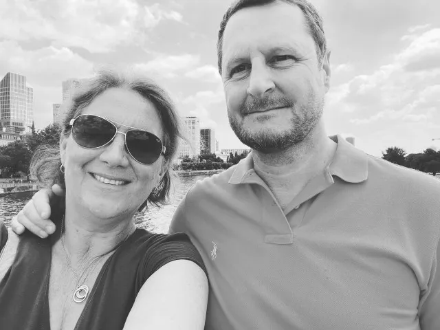 Man and woman in Frankfurt near the Main river. Water and sky scrappers behind them as they take a selfie.